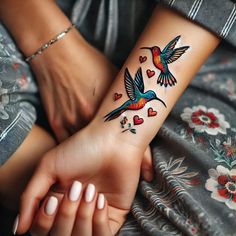 a woman's arm with two birds and hearts tattooed on the left side of her wrist