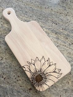 a wooden cutting board with a sunflower on it