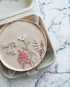 a decorated cake in a box on a marble counter top with the words happy day written on it