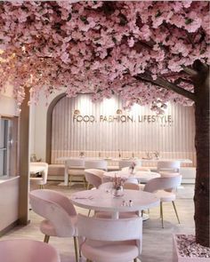 the interior of a restaurant with pink flowers on the ceiling and tables in front of it