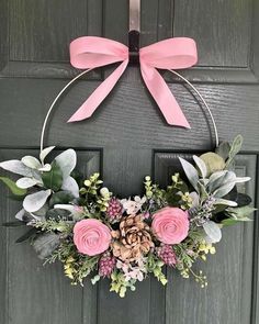 a wreath with pink flowers and greenery hanging on a door