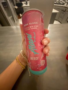 a person holding up a pink energy drink