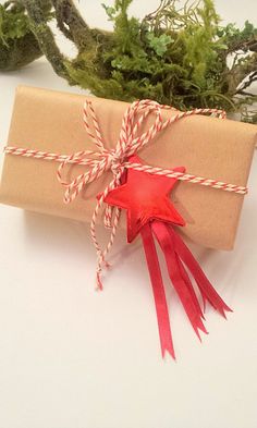 a present wrapped in brown paper and tied with red twine, sitting on a white surface