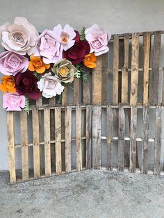 an arrangement of paper flowers is displayed on a wall