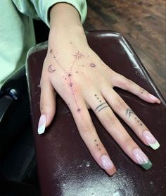 a woman's hand with stars and moon tattoos on her left hand, sitting on a chair