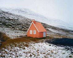 a small red house sitting on top of a snow covered hill