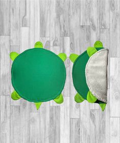 two green turtle shaped rugs sitting on top of a wooden floor