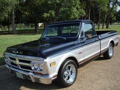 an older pickup truck parked on the side of the road in front of some trees