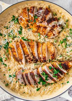 chicken with parmesan cheese and parsley in a skillet on a marble surface