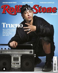 a man sitting on top of a radio next to an old fashioned boombox in front of a magazine cover