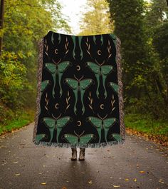 a woman is standing on the road holding a blanket with an image of two butterflies