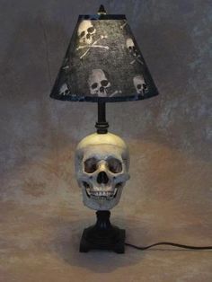 a skull lamp with a black shade on it's head and skulls painted on the lampshade