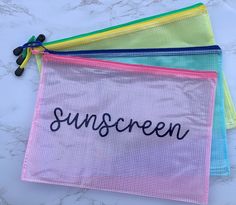 three colorful mesh bags with the word sunscreen written in black on one side, and four different colored strings attached to them