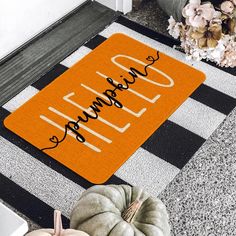 an orange welcome mat with the words hello autumn written on it next to some pumpkins