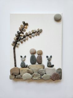 an art piece made out of rocks and stones with a tree in the middle on a white background