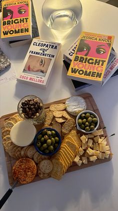 a table topped with books, crackers and olives