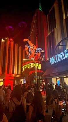 people are standing in front of a building at night with neon signs on the sides