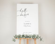 a white sign with greenery on it next to a easel