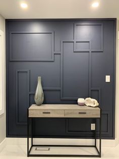 a white vase sitting on top of a table in front of a wall with blue paneling