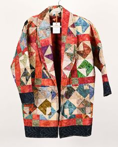 Quilt Coats are our favorite way to cozy up in something repurposed. Great and unique outer layer for the colder months. Be the showstopper in your daily life with a Quilt Coat! The quilt used to make this coat uses a cream base and jewel tones. A flourish of reds and oranges frame the "flying goose" patterned blocks made from the deep purples, greens, and aquamarines. Size: Small Wingspan: 59" Base of neck to waist: 33" Waist: 46" Size Chart According to Pattern: XS: 6-8 Small: 10-12 Medium: 14-16 Large: 18-20 Care Instructions: Spot clean when possible. Wash inside out with cold water and lay flat to dry. Flying Goose, Wine Gift Bag, Cream Base, Flying Geese, Aqua Marine, Small Quilts