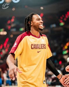 a man with dreadlocks standing in front of a basketball court and shaking hands