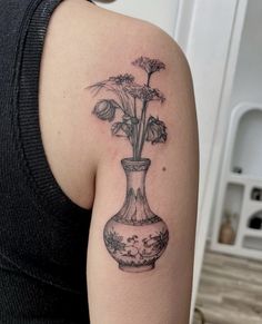 a woman with a tattoo on her arm has a vase with flowers in it