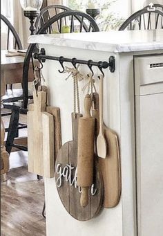 a kitchen island with cutting boards hanging from it's hooks and wooden utensils