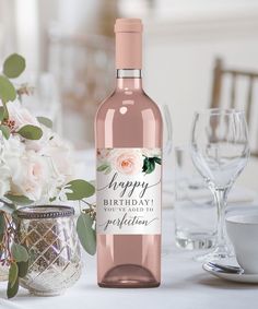 a bottle of pink wine sitting on top of a table next to glasses and flowers