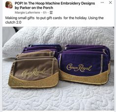 two purple and gold purses sitting on top of a white bed next to each other