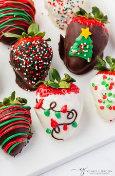 chocolate covered strawberries are arranged on a white platter with christmas decorations and sprinkles