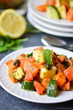 a white plate topped with carrots and cucumbers next to a lemon wedge