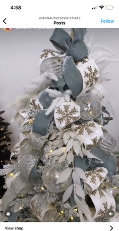 a christmas tree decorated with silver and white ribbons, snowflakes, and lights