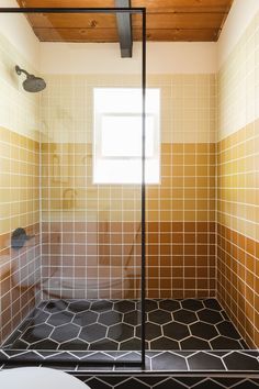 a bathroom with tiled walls and flooring in the shower area, along with a toilet