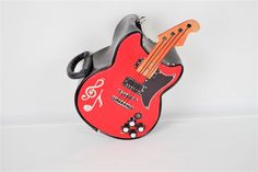 a red guitar shaped purse with black handles and buttons on the front, sitting against a white background