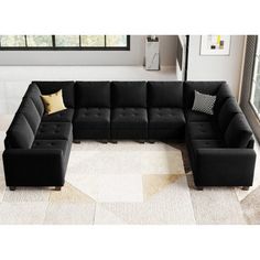 a living room with a black sectional couch and pillows on the floor in front of a large window