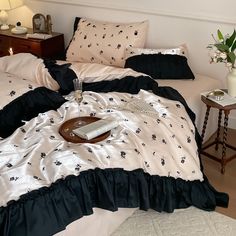 two beds with black and white comforters in a bedroom next to a night stand