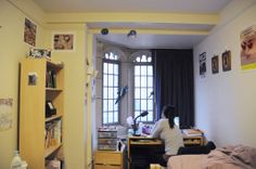 a woman sitting at a desk in front of a window next to a book shelf