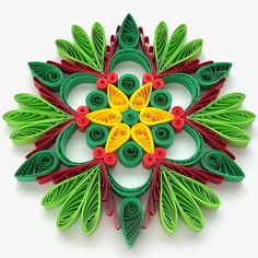 an intricate paper quilling design made from green, red and yellow leaves on white background