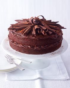 a chocolate cake sitting on top of a white plate next to a knife and fork