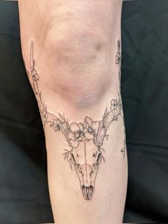 a tattoo on the leg of a woman with flowers and an animal's skull