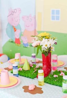 there is a table set up with pink and yellow flowers in a red vase on the grass