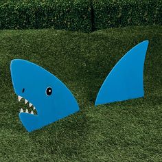 two blue shark shaped sculptures sitting in the grass