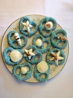 a plate topped with cookies covered in blue icing and seashells on top of a white table cloth