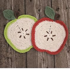 two crocheted apples sitting on top of a wooden table next to each other