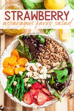 strawberry asparagus farro salad in a bowl on a wooden table with lemons and strawberries