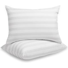 a white pillow sitting on top of a bed next to a striped pillow cover and pillows