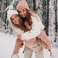 two young women are hugging in the snow