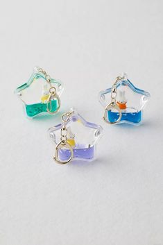 three different colored glass charms on a white surface