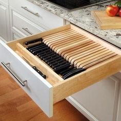 an open drawer in the middle of a kitchen with cutting board and knifes on it