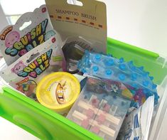 a green bin filled with lots of toys and candy bars on top of a table